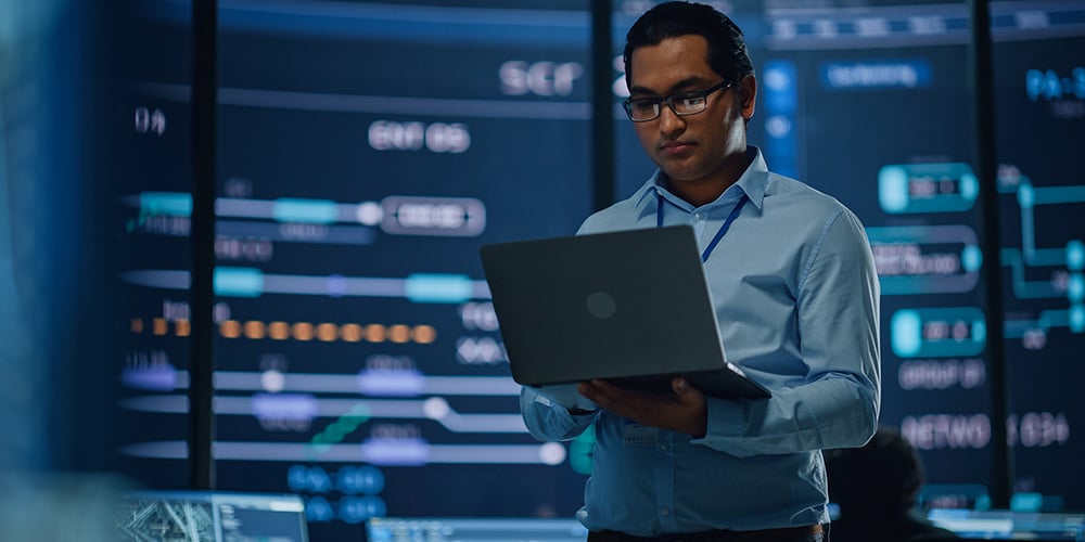 Man typing on a laptop whilst standing up